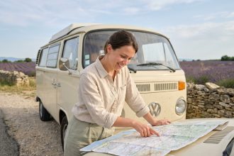 Femme planifiant un road trip sur une carte routière dépliée sur un camping-car vintage en Provence