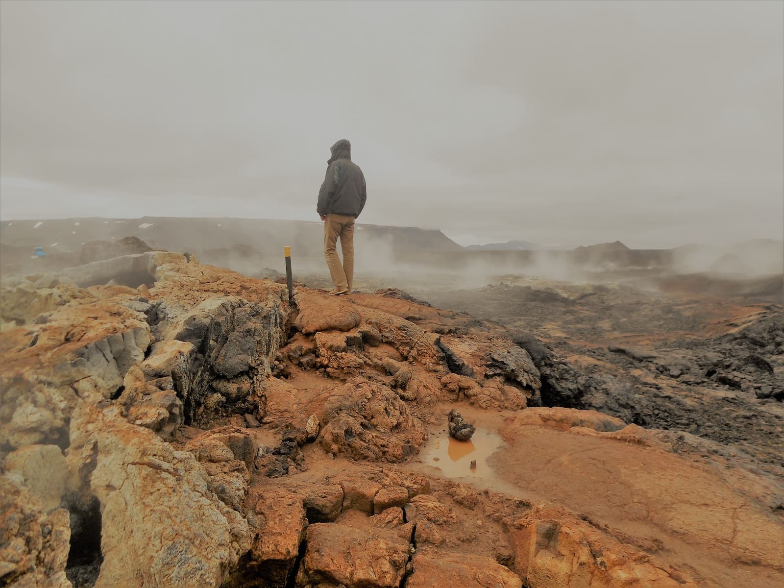 man in black jacket standing on brown rock formation during daytime