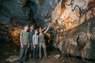 Famille visitant une grotte préhistorique en Dordogne avec peintures rupestres sur paroi calcaire
