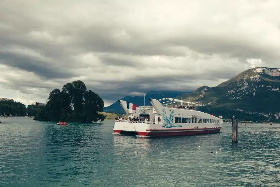 white and red passenger boat floating on body of water near island